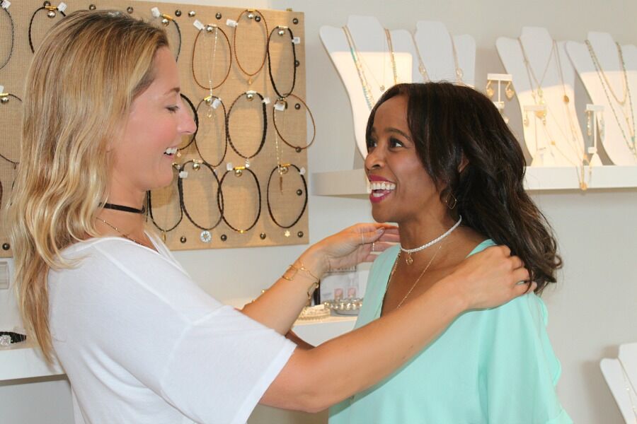 woman helping another woman put on AC4 Choker for Summer Accessory Trends woman helping another woman put on AC4 Choker for Summer Accessory Trends
