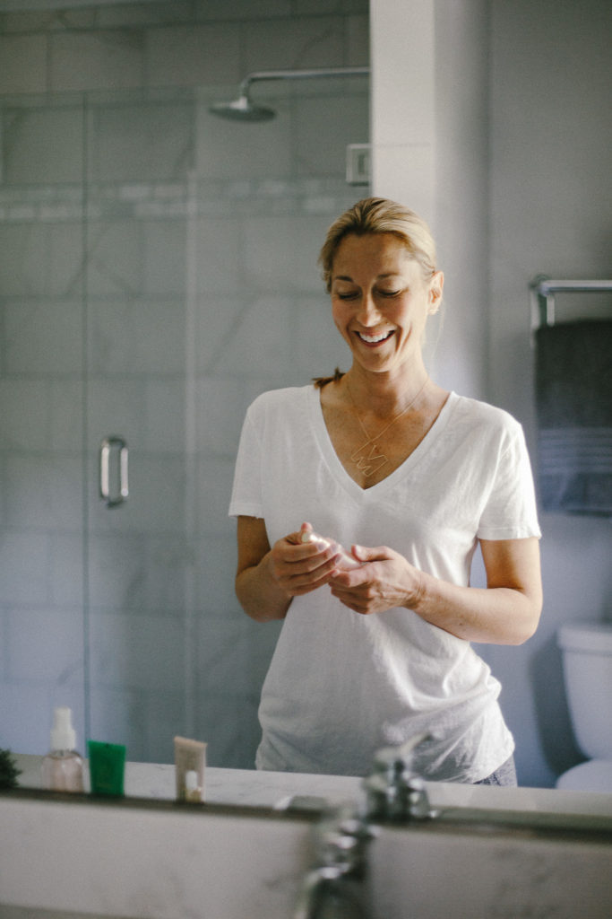woman in a bathroom woman in a bathroom holding a beauty Clean Beauty Brands