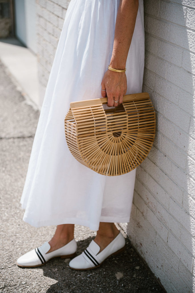 woman wearing one of the white summer dresses, white shoes, and holding a handbag woman wearing one of the white summer dresses, white shoes, and holding a handbag