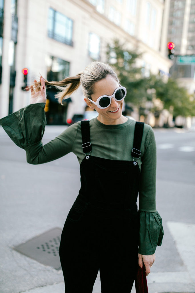 woman touching her hair and wearing velvet overalls woman touching her hair and wearing velvet overalls