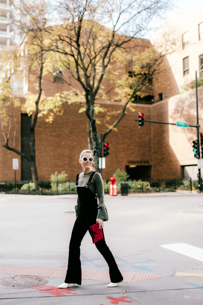 woman Pairing Velvet Overalls with a Statement Top and Velvet Clutch woman Pairing Velvet Overalls with a Statement Top and Velvet Clutch