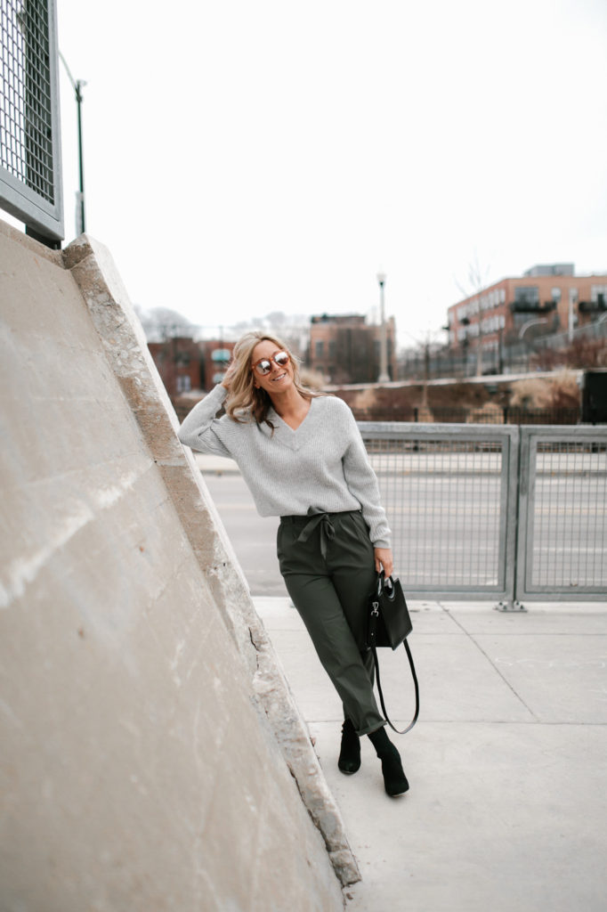 woman leaning woman wearing gray shirt, paper-bag pant, and holding a bag
