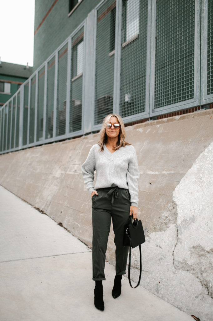woman standing woman wearing paper-bag pant, great sweatshirt, and one hand in her pocket