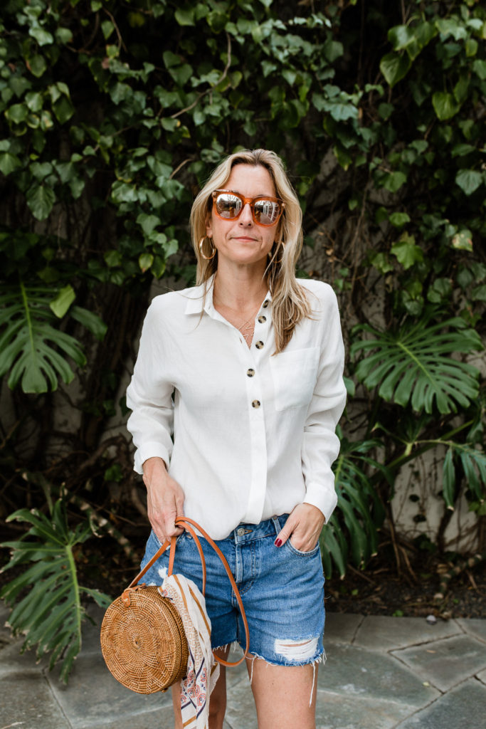 woman hands in pockets and wearing denim shorts and White Essentials for Spring woman hands in pockets and wearing denim shorts and White Essentials for Spring