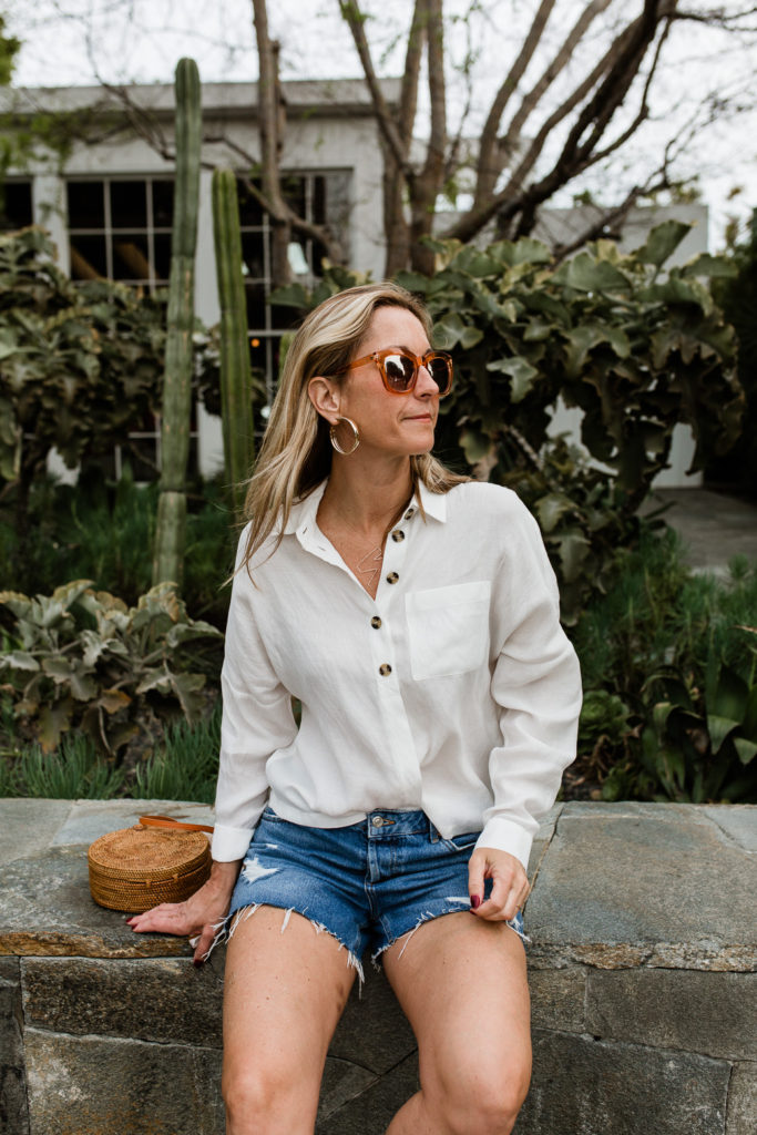 woman sitting and wearing denim shorts and White Essentials for Spring woman sitting and wearing denim shorts and White Essentials for Spring