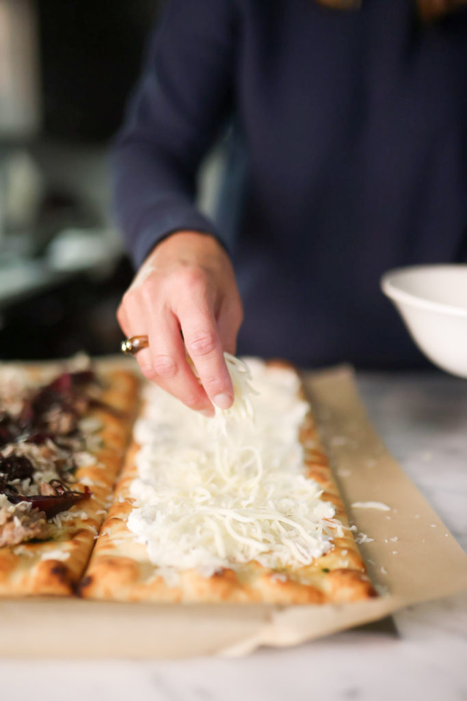 person adding cheese on flatbreads person adding cheese on flatbreads